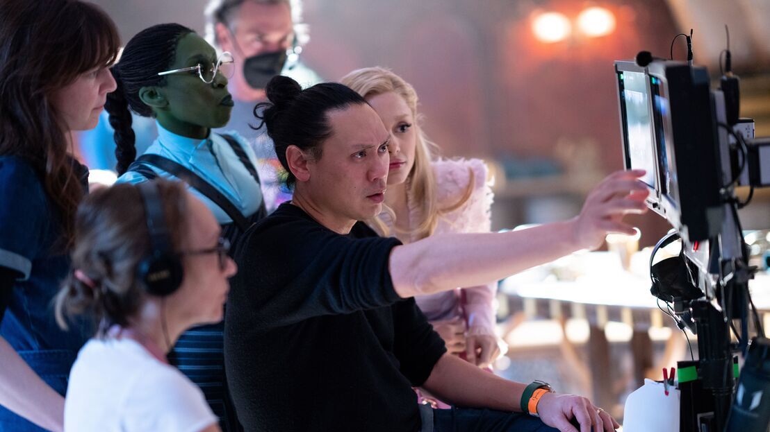 Centre L-R - Cynthia Erivo (as Elphaba), Director Jon M. Chu, and Ariana Grande (as Glinda) on the set of Wicked